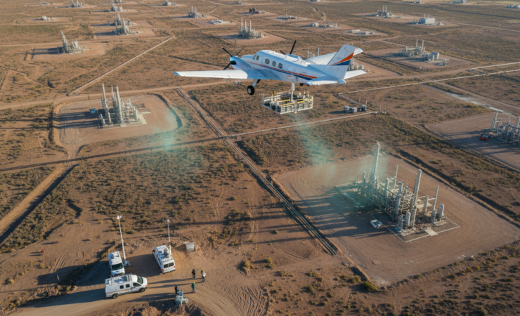 Aerial editorial view of an oil and gas field with methane monitoring equipment surveying dispersed facilities